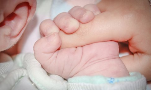 赤ちゃんの手に指を握らせる親